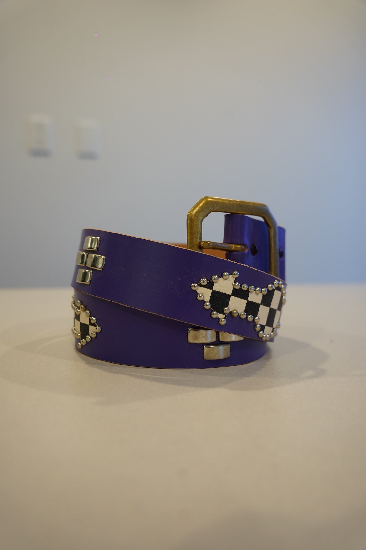 Vintage coiled purple leather belt with brass buckle, silver square studs and black-white checker studded diamonds.