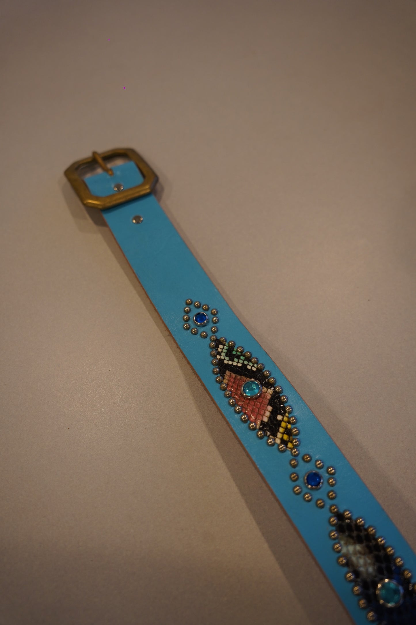 Vintage light blue snakeskin studded belt detail showing pink, green and yellow beadwork and gem accents