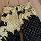 Louis Vuitton bleach monogram jeans close-up of gold bleach splatter wash detail over LV pattern on wood floor