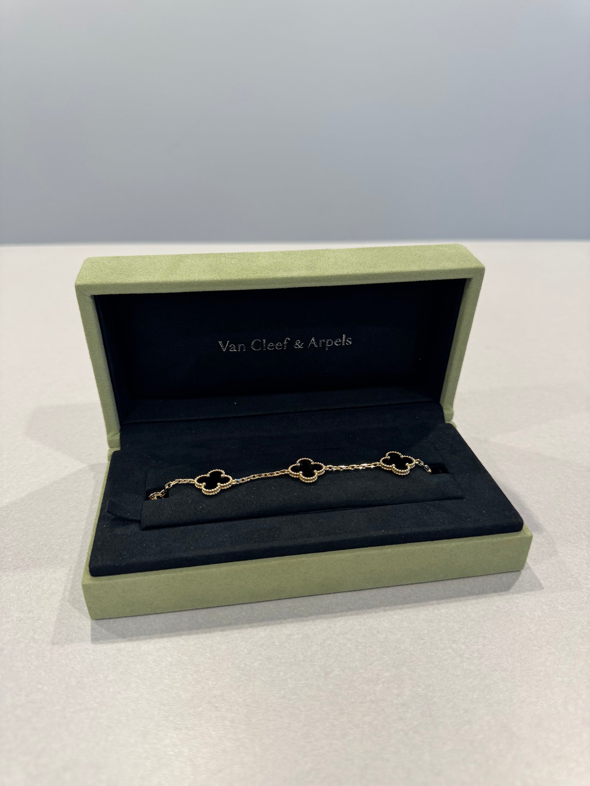 Van Cleef & Arpels onyx Alhambra bracelet close-up of 5 clover motifs in 18k yellow gold chain