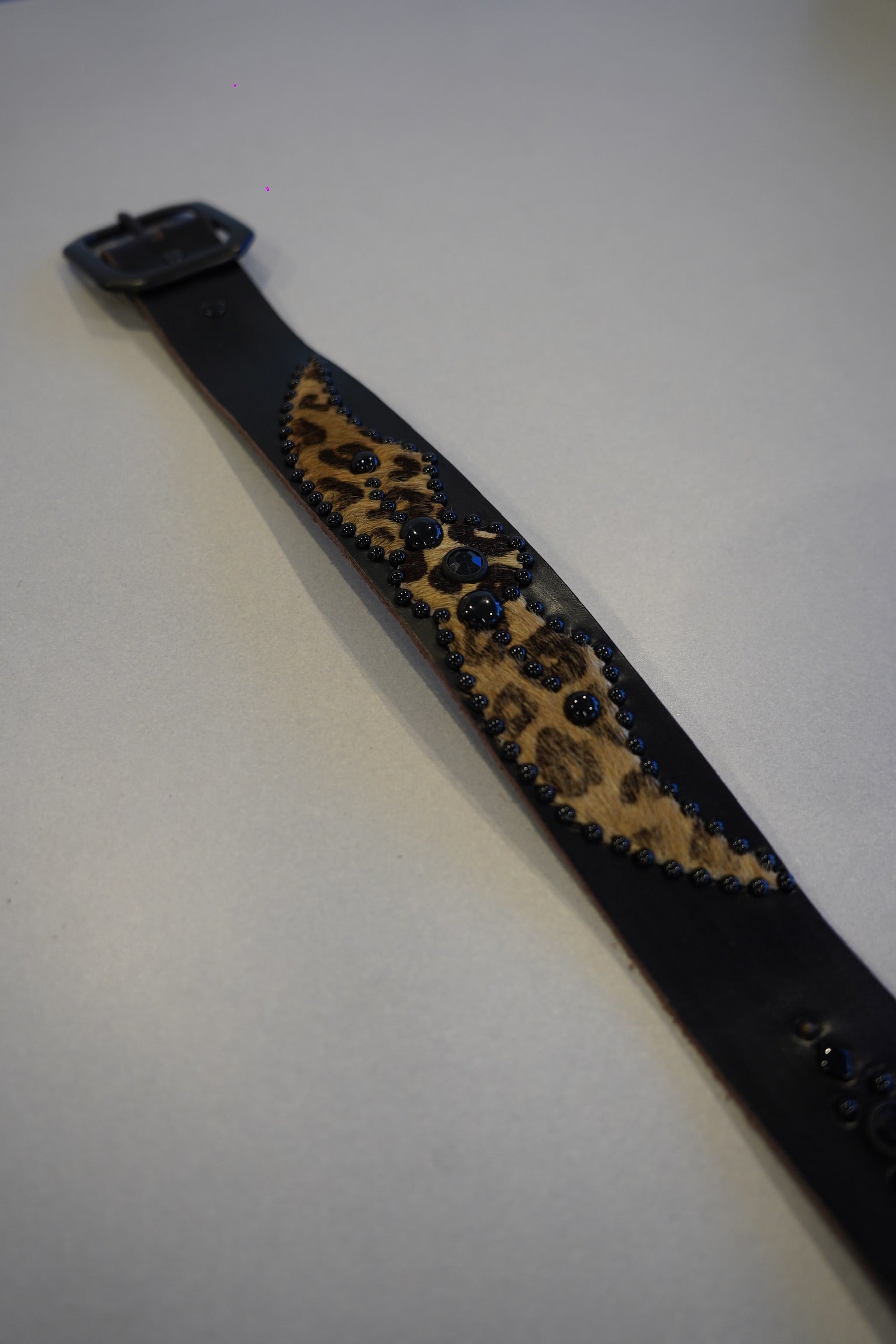 Vintage black winged cheetah print studded leather belt flat view, animal pattern and silver studs