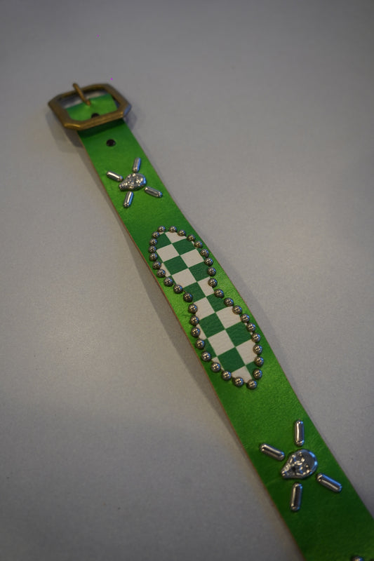 Vintage green checkered studded belt close-up detail of metal buckle and pyramid stud row