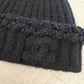 Chanel black beanie folded flat showing soft ribbed cashmere knit and embossed CC logo embellishment.