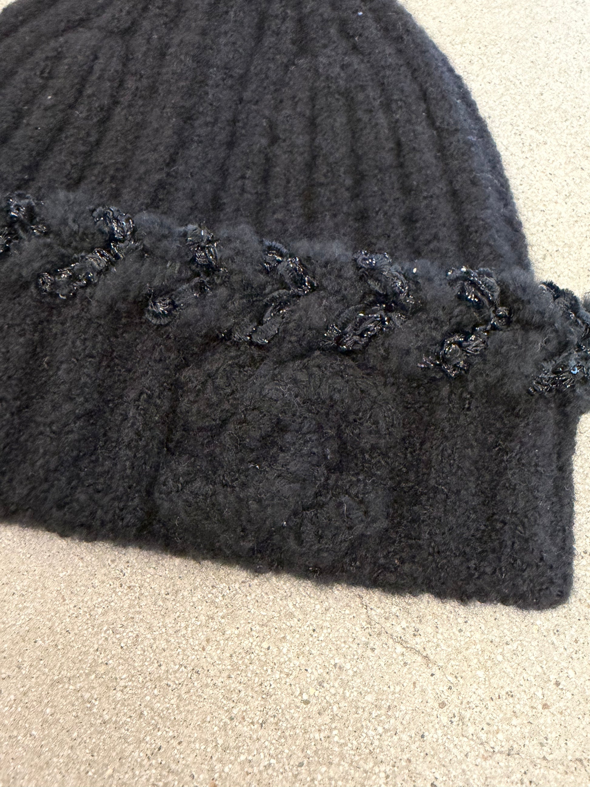 Chanel black beanie folded flat showing soft ribbed cashmere knit and embossed CC logo embellishment.