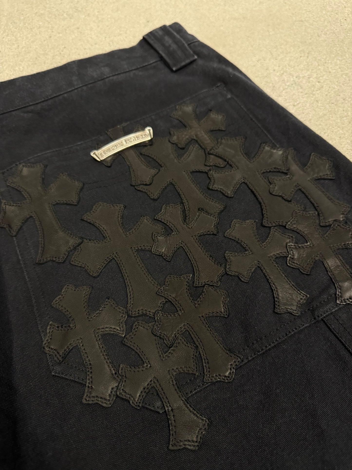 Chrome Hearts carpenter shorts close-up of black leather flooded cross patches stitched on back pocket