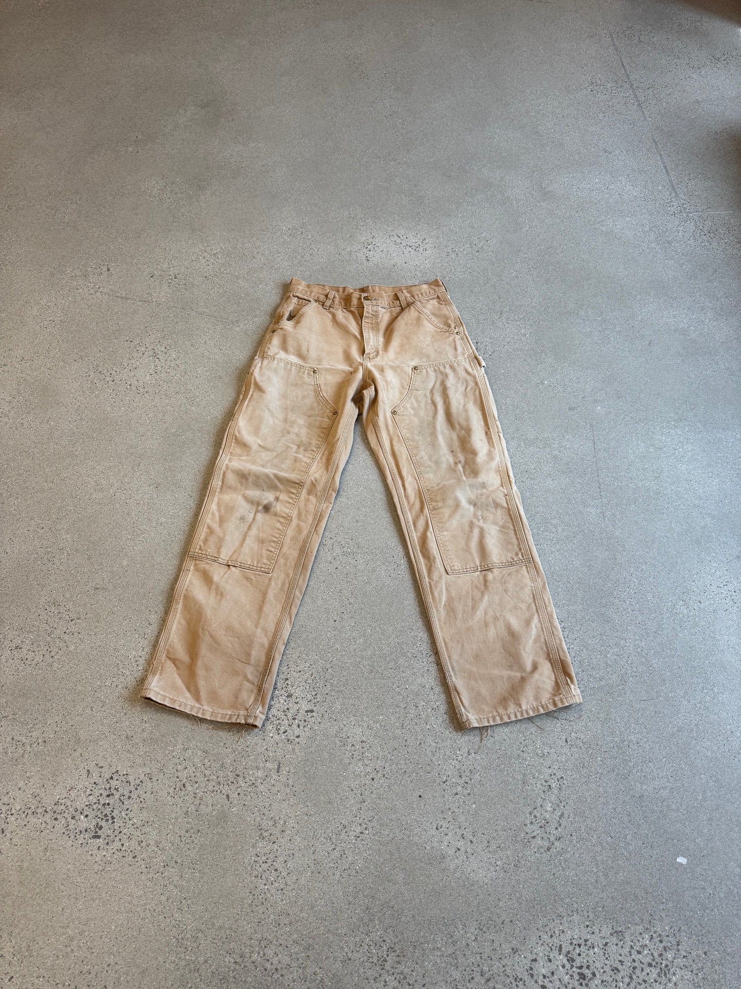 Vintage Carhartt tan double-knee carpenter pants in faded duck canvas with reinforced knee panels and utility loops.