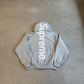 Supreme heather gray hoodie laid flat with large vertical white Supreme satin applique logo across back