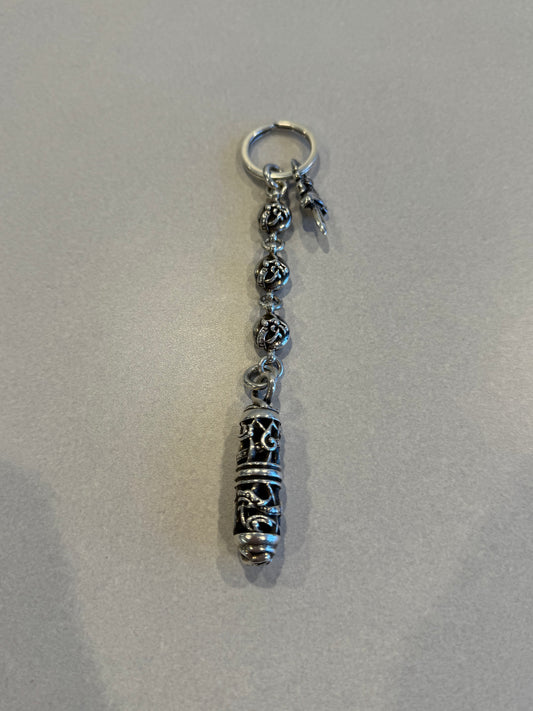 Chrome Hearts Celtic dagger key ring close-up view of engraved silver capsule pendant and beaded links