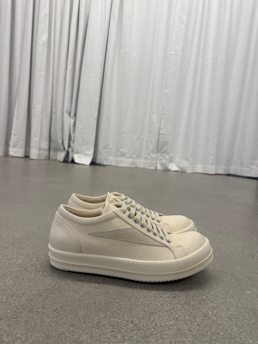 Rick Owens DRKSHDW milk vintage low-top sneakers side angle on concrete floor with curtain backdrop