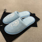 Pair of Chrome Hearts St Barths blue plush slippers displayed on black drawstring dust bag, top view