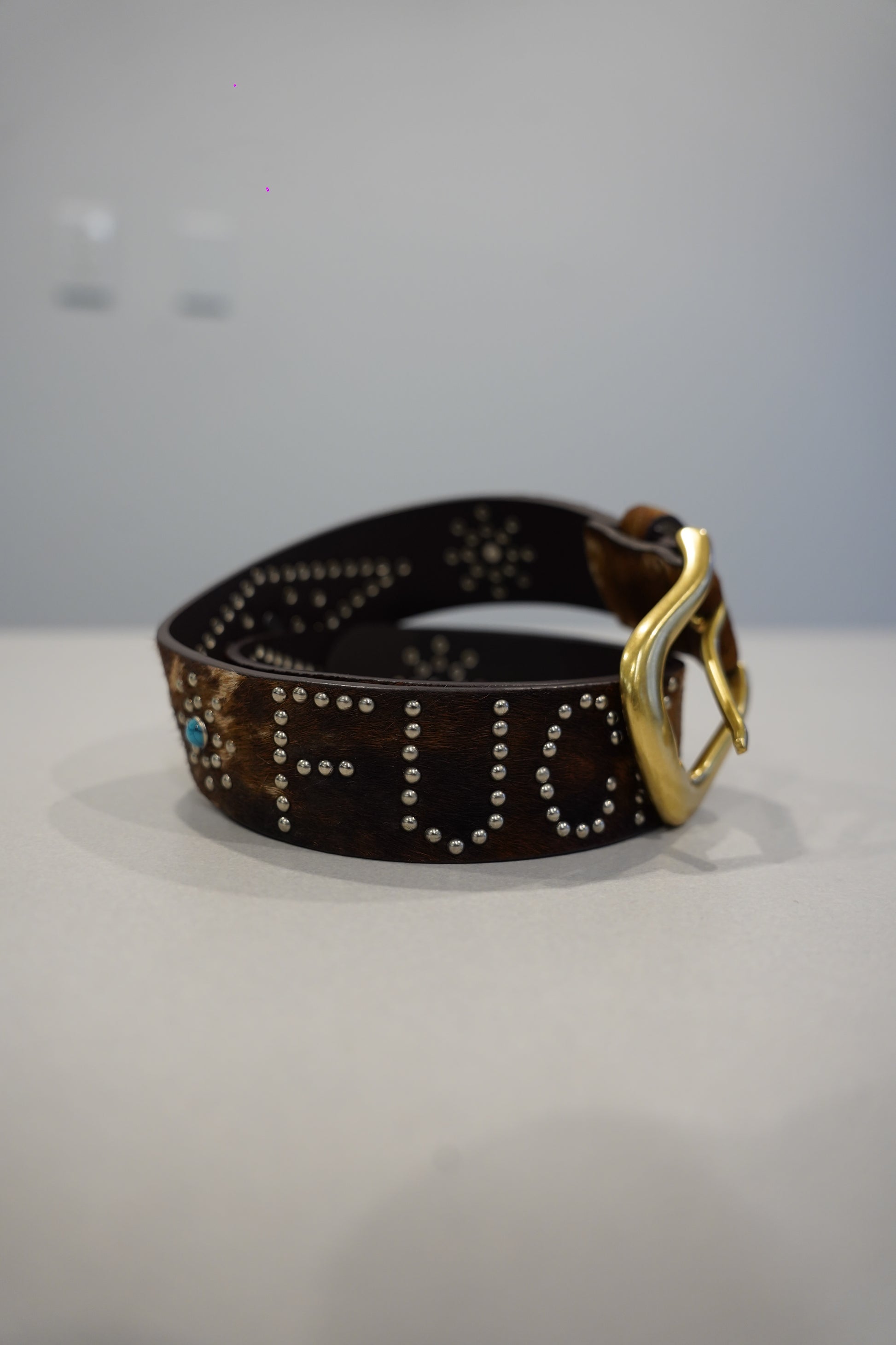 Custom brown cowhide studded belt with brass horseshoe buckle, turquoise stones and FU studded text.