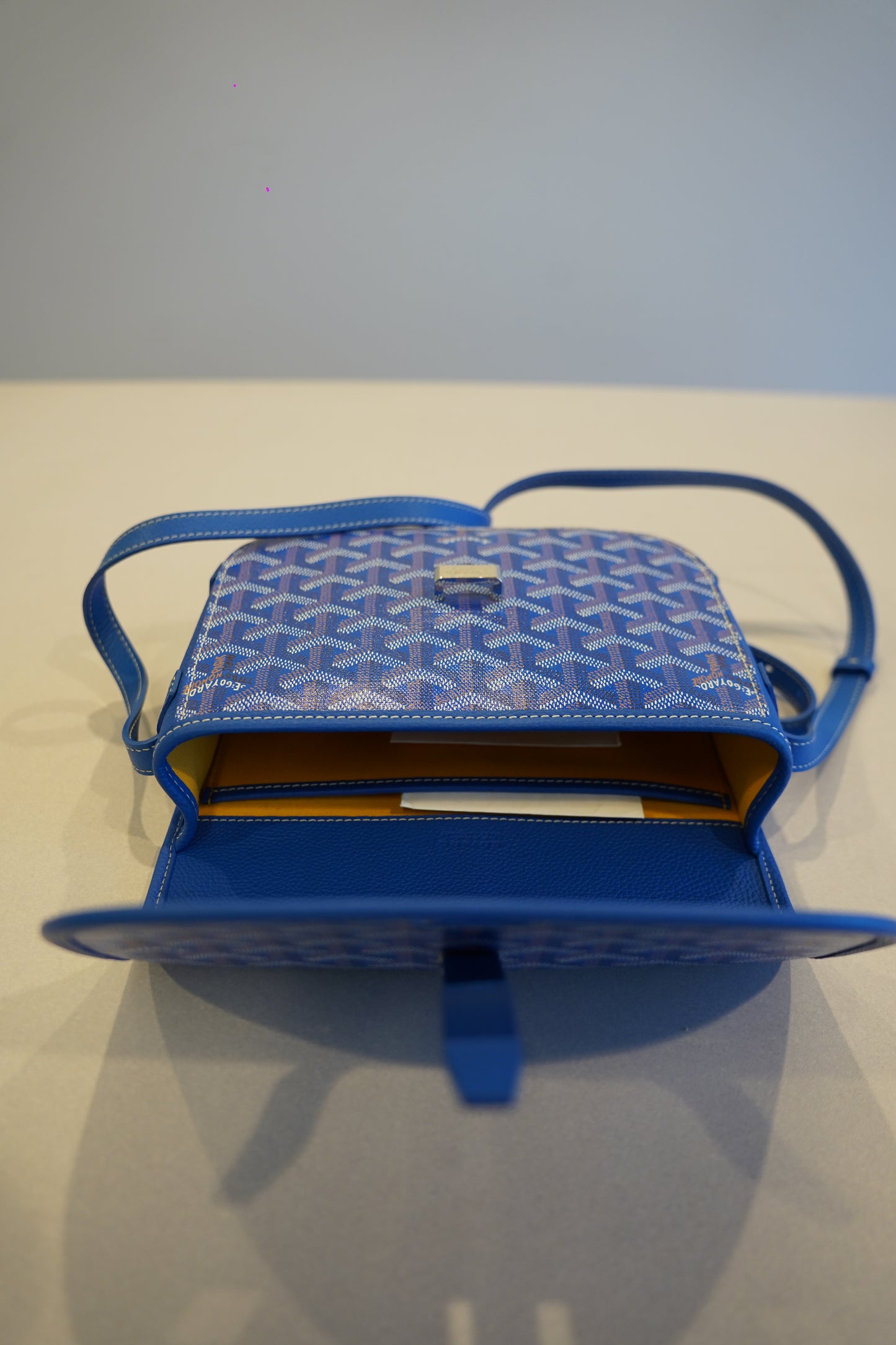 Goyard blue Belvedere PM shoulder bag opened revealing yellow interior lining and pebbled leather pocket trim.