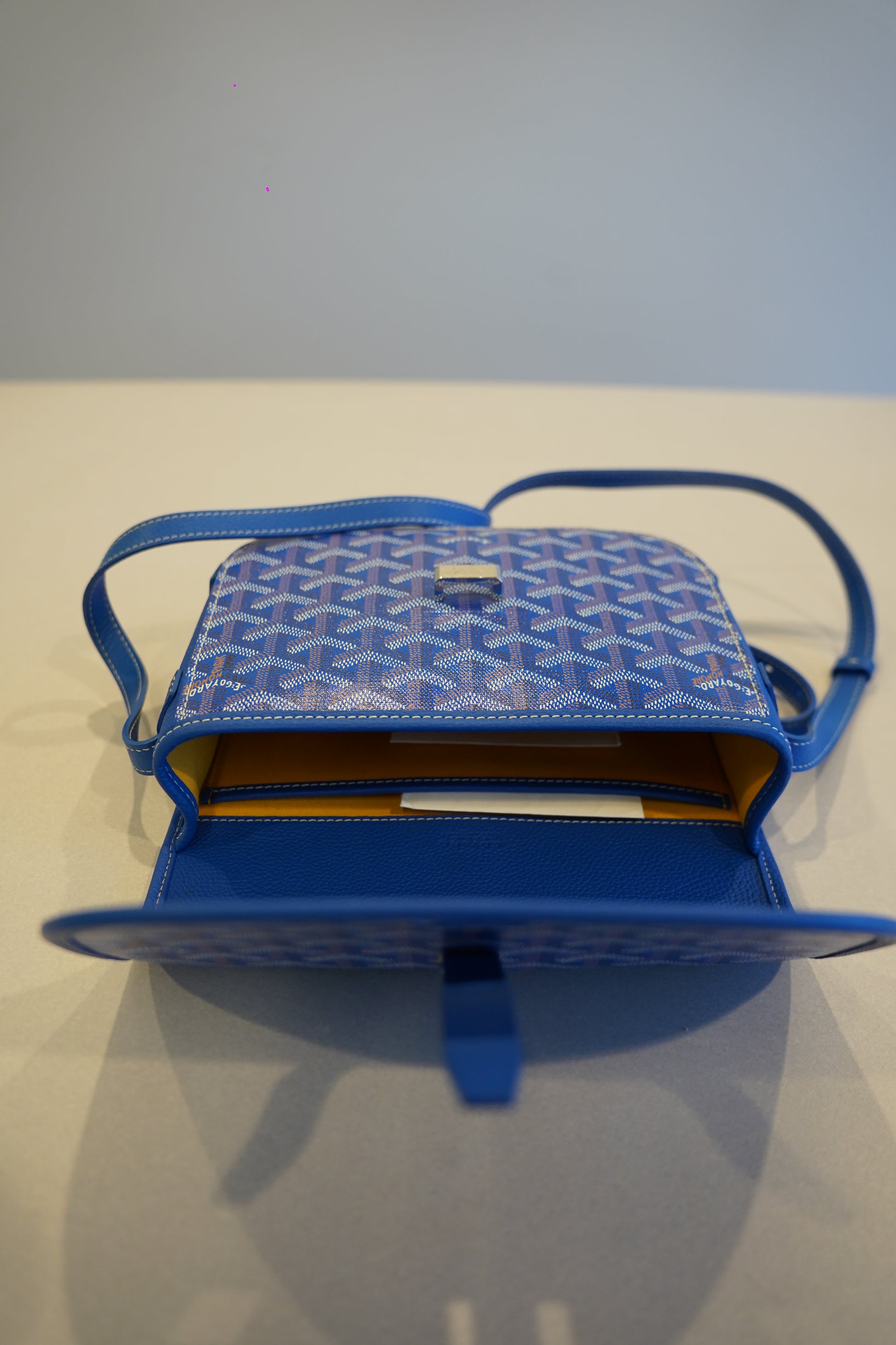Goyard blue Belvedere PM shoulder bag opened revealing yellow interior lining and pebbled leather pocket trim.