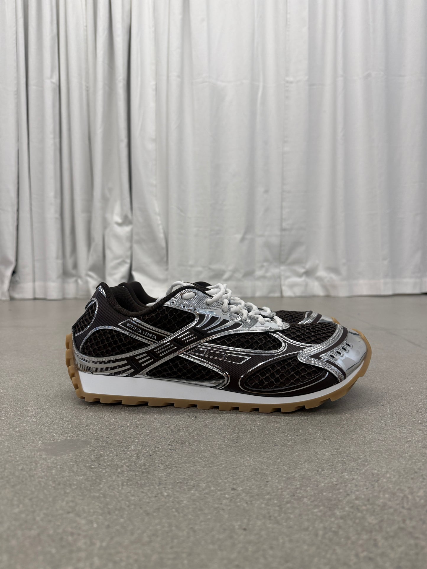 Bottega Veneta brown Orbit sneakers side profile with mesh upper, silver chrome overlays and gum rubber sole