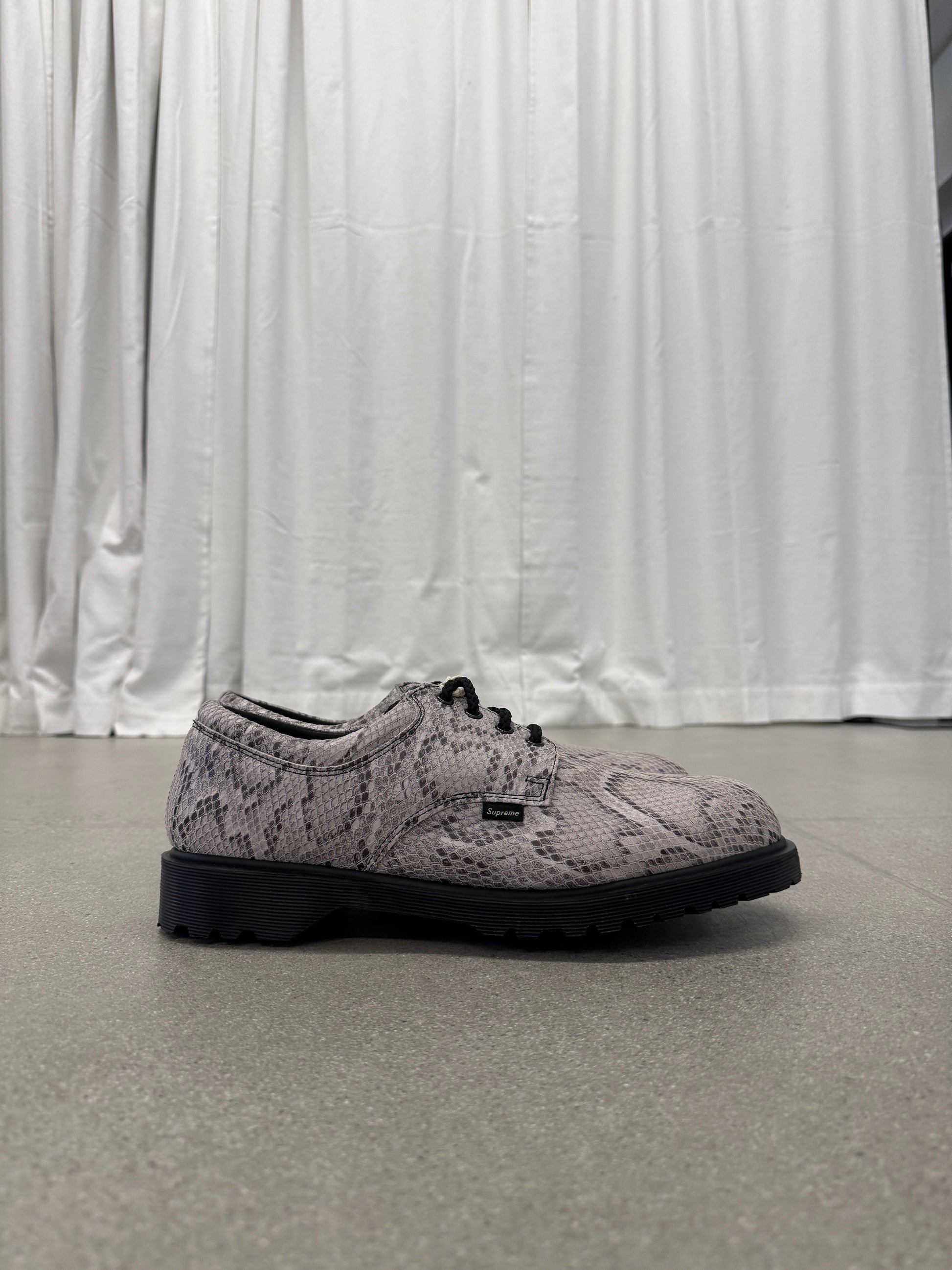 Supreme Dr Martens Postal 4-eye shoe side view in grey python snakeskin with chunky black lugged sole