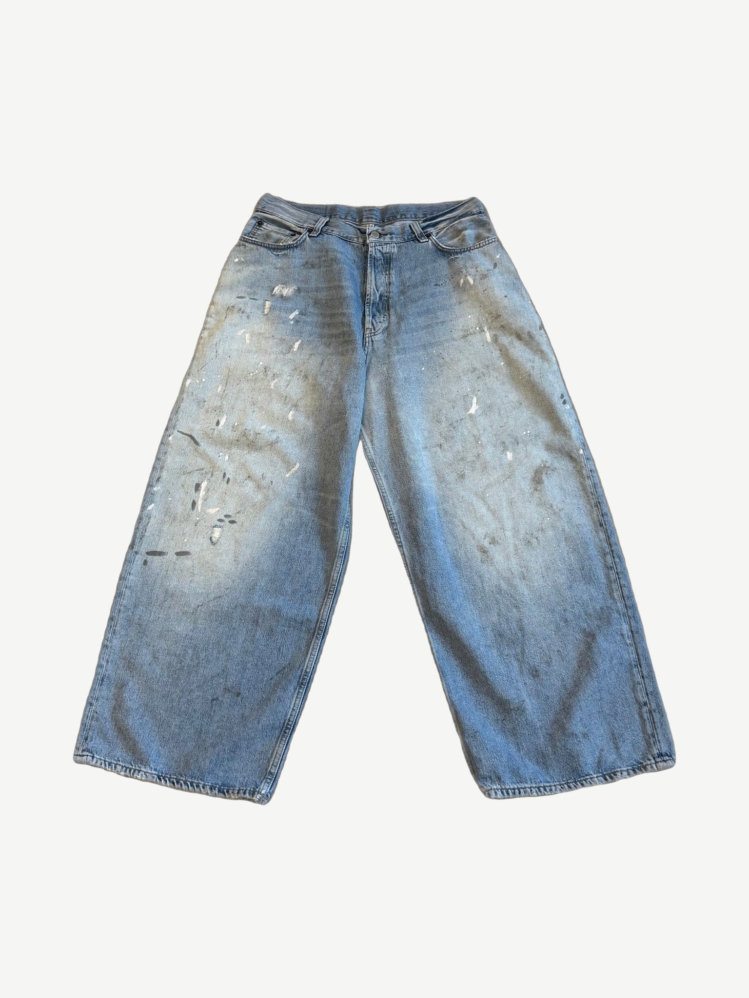 Acne Studios 2023M loose fit jeans front, light wash baggy denim with white paint splatter and dirt smudges.