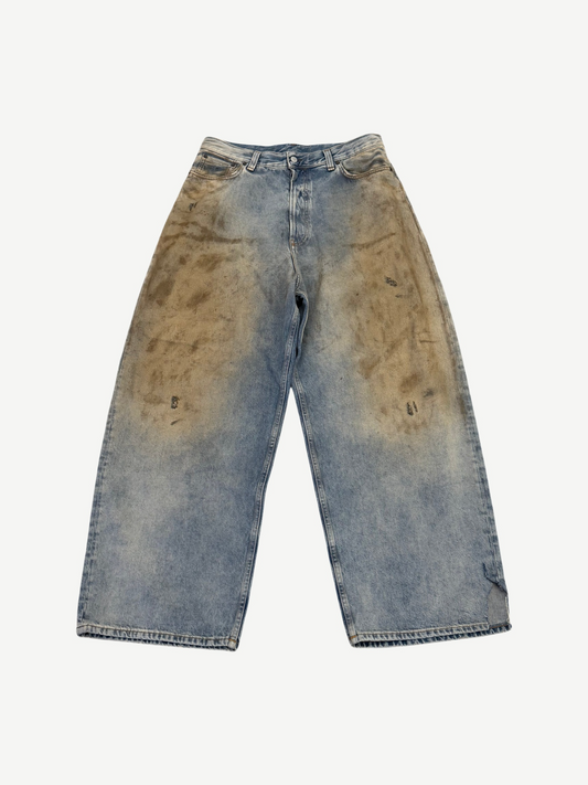 Acne Studios Penicillin baggy jeans front view in light blue denim with brown mud-wash front thigh staining