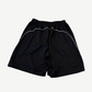 Back of Balenciaga Lamborghini black baggy shorts with white piping along seams and elastic waistband.