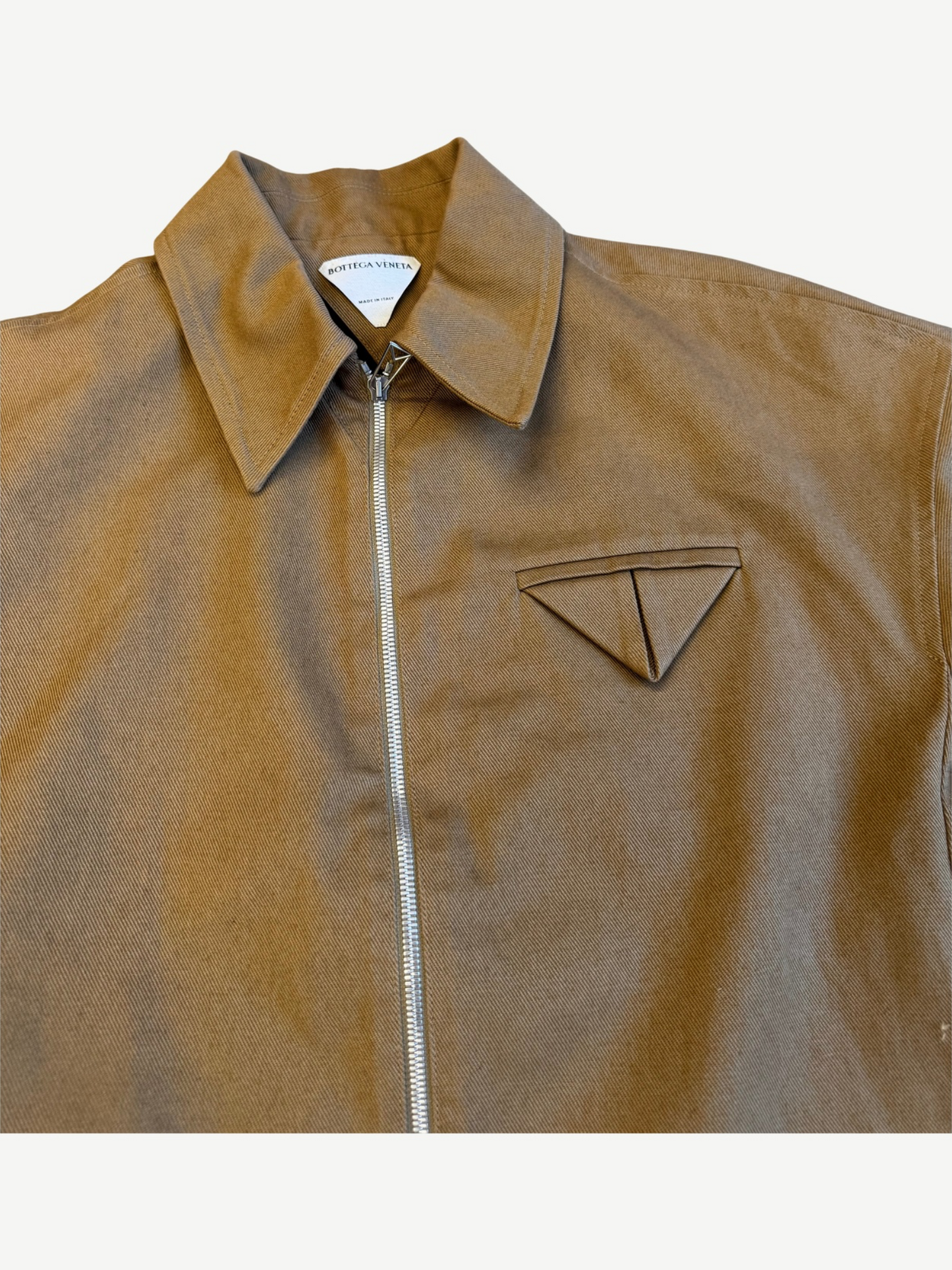 Bottega Veneta tan twill jacket close up showing triangle chest pocket emblem and silver zip detail