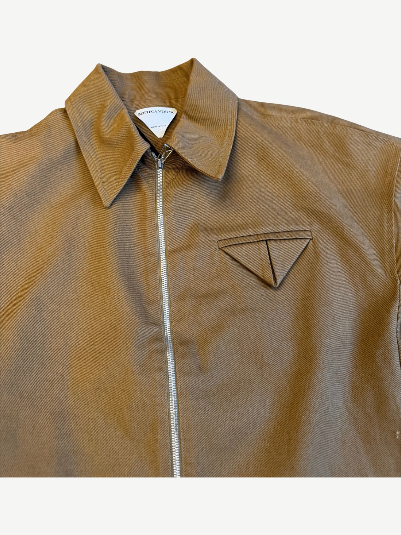 Bottega Veneta tan twill jacket close up showing triangle chest pocket emblem and silver zip detail