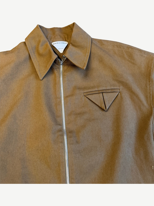 Bottega Veneta tan twill jacket close up showing triangle chest pocket emblem and silver zip detail