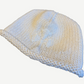 Chrome Hearts cream knit beanie angled view with thick rolled brim and beaded ivory cross applique on side.
