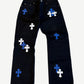Chrome Hearts black jeans front, scattered blue and white leather cross patches with fleur knee dagger appliques.