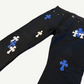 Chrome Hearts black fleur knee jeans angled detail, blue white leather cross patches clustered along leg seam.