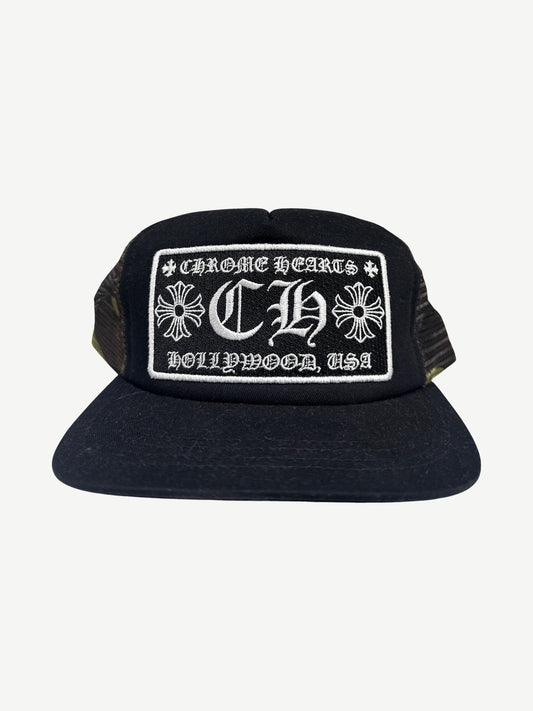 Chrome Hearts Hollywood trucker hat with black camo crown, white mesh back and embroidered CH front patch.