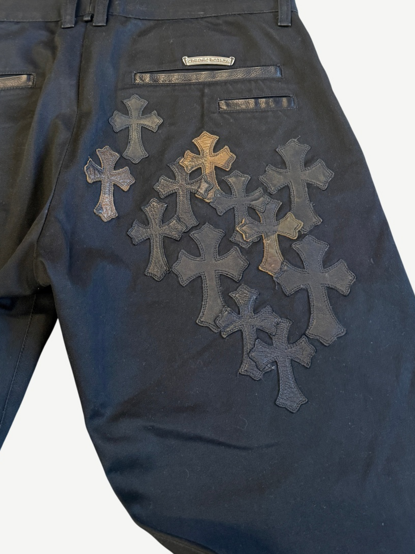 Chrome Hearts cross patch chinos rear detail close-up of layered black leather crosses on back pocket
