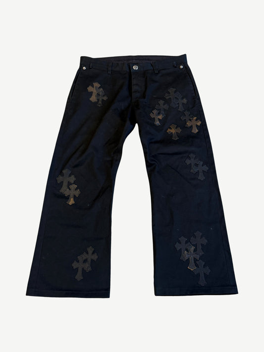 Chrome Hearts black chino pants front with scattered leather cross patches and silver CH button hardware