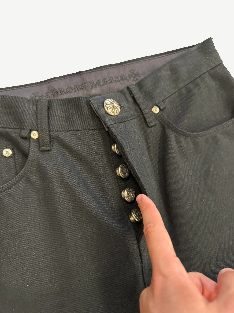 Chrome Hearts black jeans close-up of silver dagger button fly and Chrome Hearts gothic waistband lining