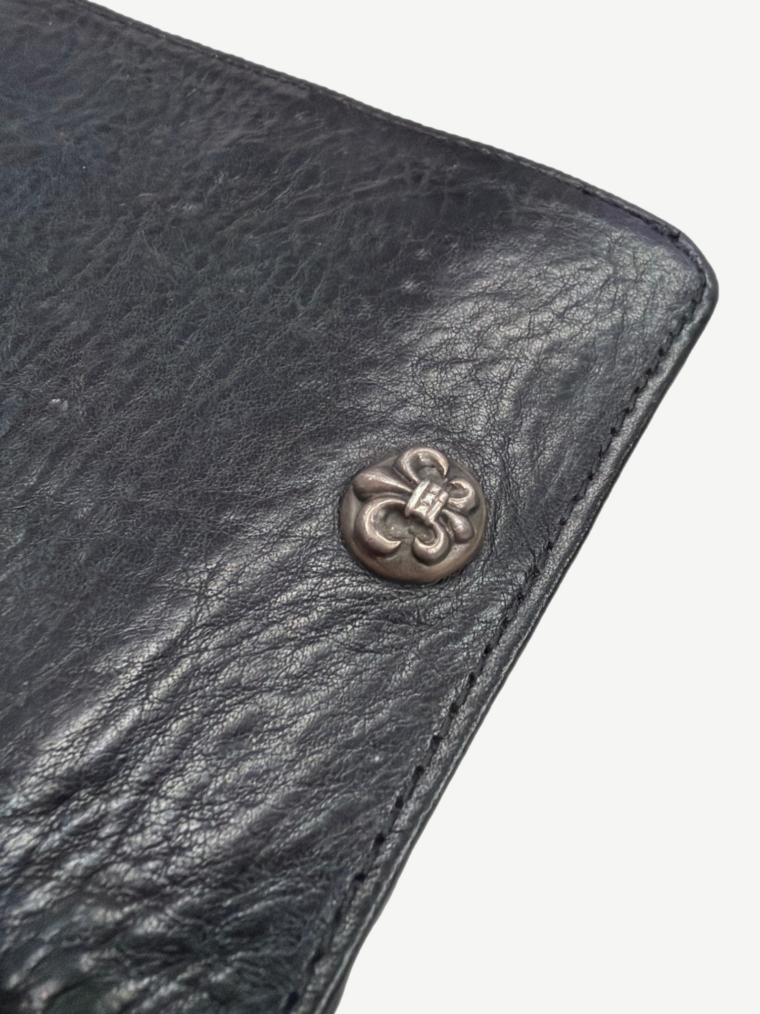 Chrome Hearts black leather wallet close up of sterling silver fleur de lis snap hardware on grained leather