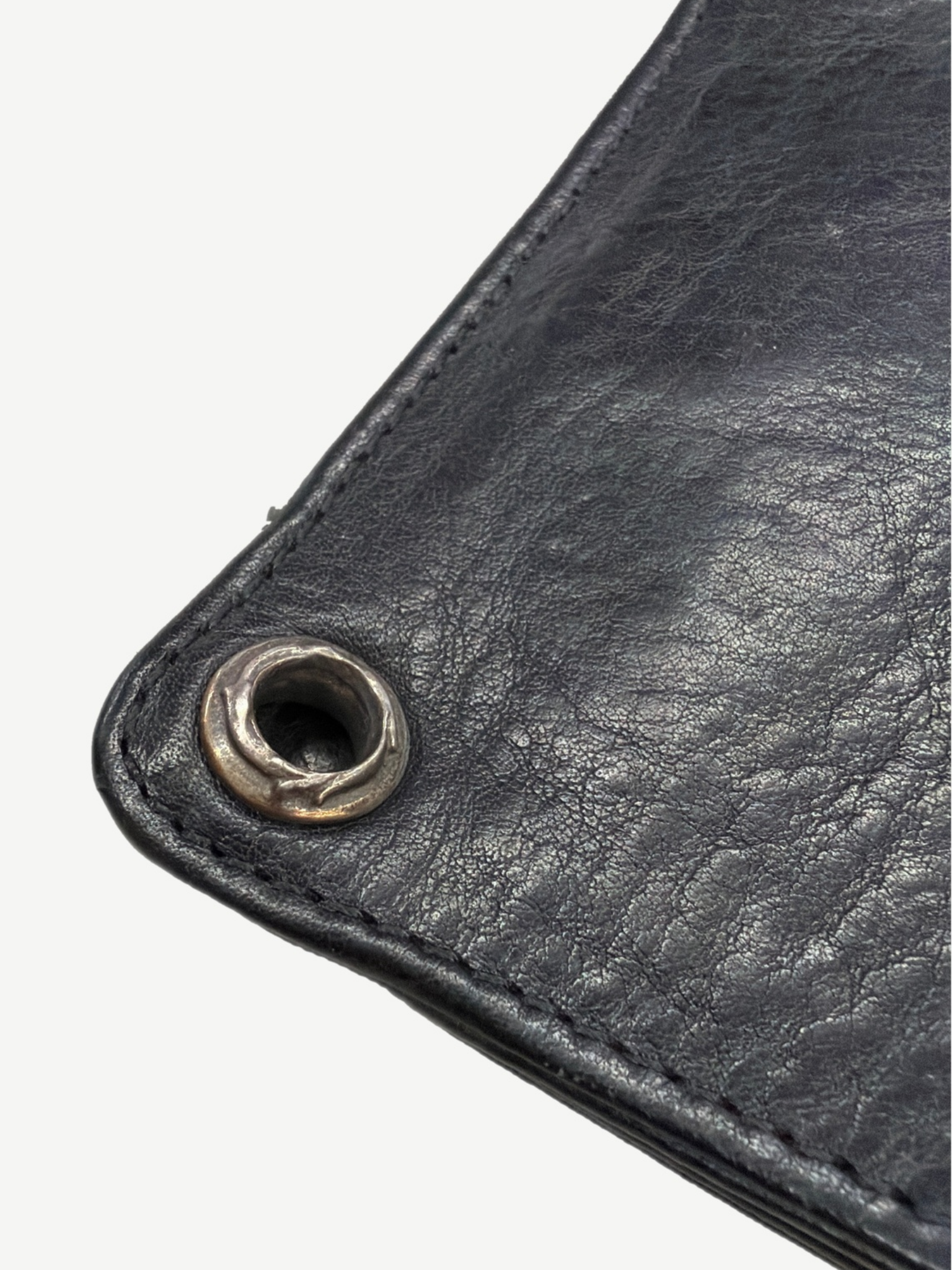 Chrome Hearts black leather wallet corner detail showing silver grommet eyelet and topstitched leather grain