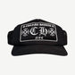 Chrome Hearts NYC CH trucker hat in black with white embroidered gothic CH cross logo patch on foam front.