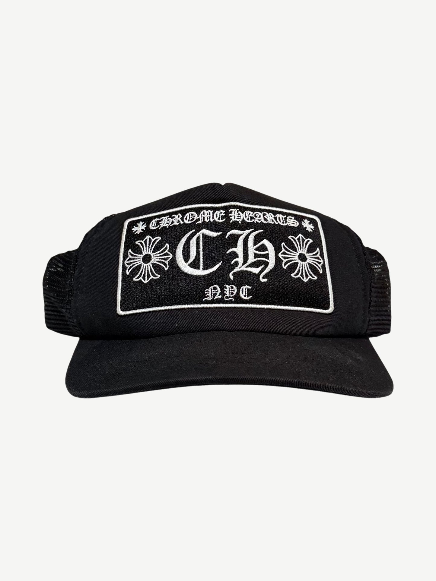 Chrome Hearts NYC CH trucker hat in black with white embroidered gothic CH cross logo patch on foam front.