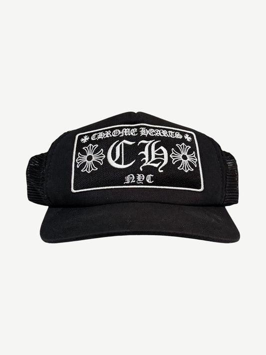 Chrome Hearts NYC CH trucker hat in black with white embroidered gothic CH cross logo patch on foam front.