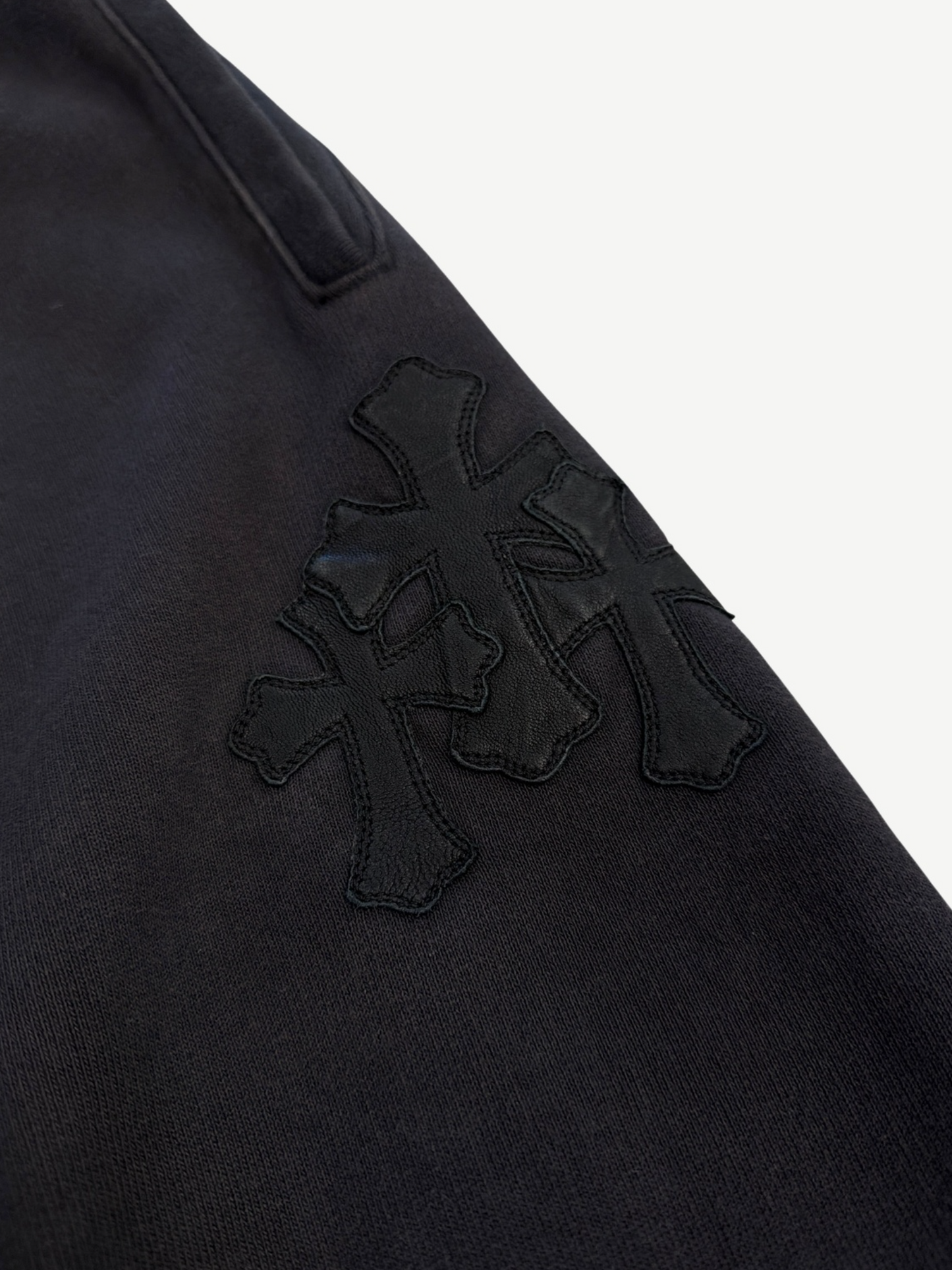 Chrome Hearts Paper Jam sweatpants close-up of stacked black leather cross patch cluster on thigh