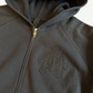 Chrome Hearts Paper Jam zip up close up of tonal black triple cross applique and gold zipper hardware.