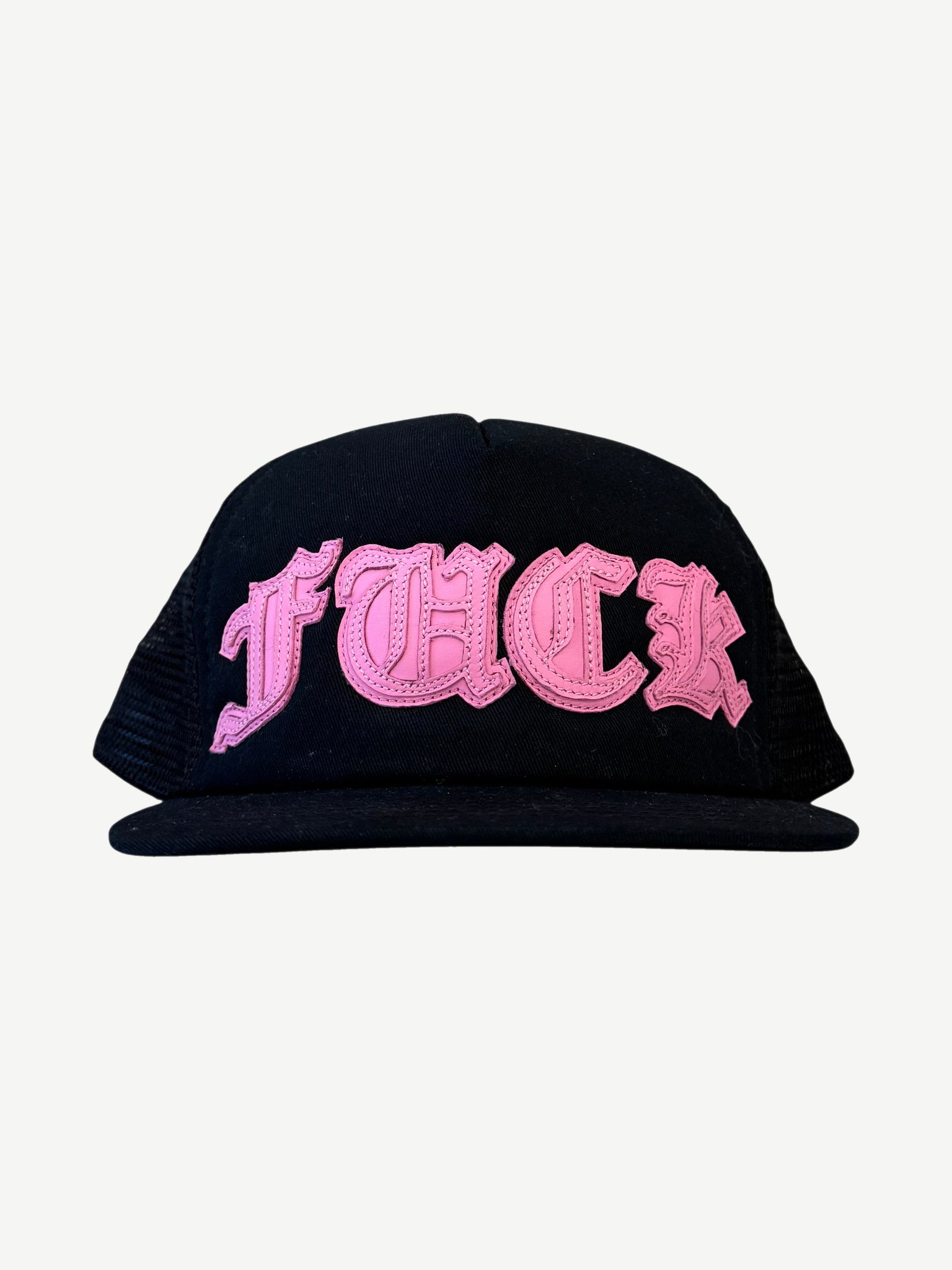 Chrome Hearts black mesh trucker hat with pink Old English Fuck leather patch across front panel.