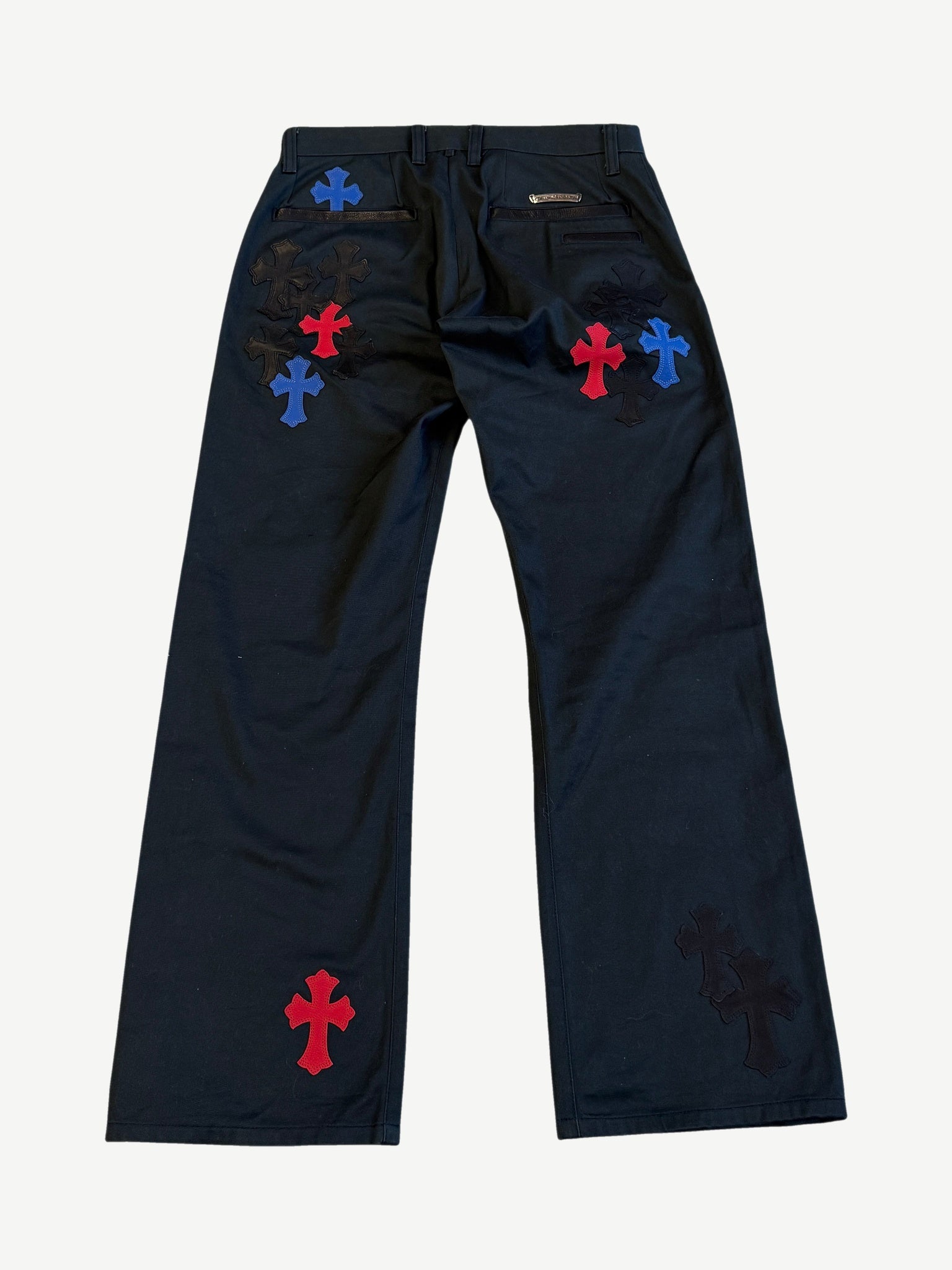Chrome Hearts black cross patch chinos back view showing red and blue leather cross patches across the seat.