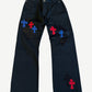 Chrome Hearts black chino pants front covered in stitched black, red and blue leather cross patches at thighs.