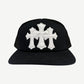Chrome Hearts black trucker hat front with three white leather cross patches stitched across the crown panels.