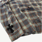 Chrome Hearts cross patch plaid flannel detail showing leather cross patch on sleeve and gray orange plaid weave.