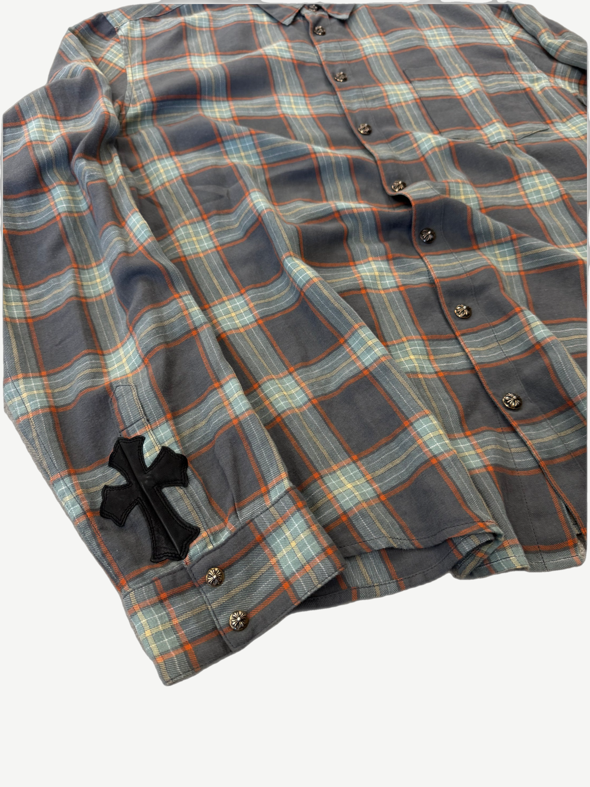 Chrome Hearts cross patch plaid flannel detail showing leather cross patch on sleeve and gray orange plaid weave.