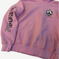 Chrome Hearts Matty Boy pink hoodie cropped detail showing checker smiley face patch and Hearts sleeve script.