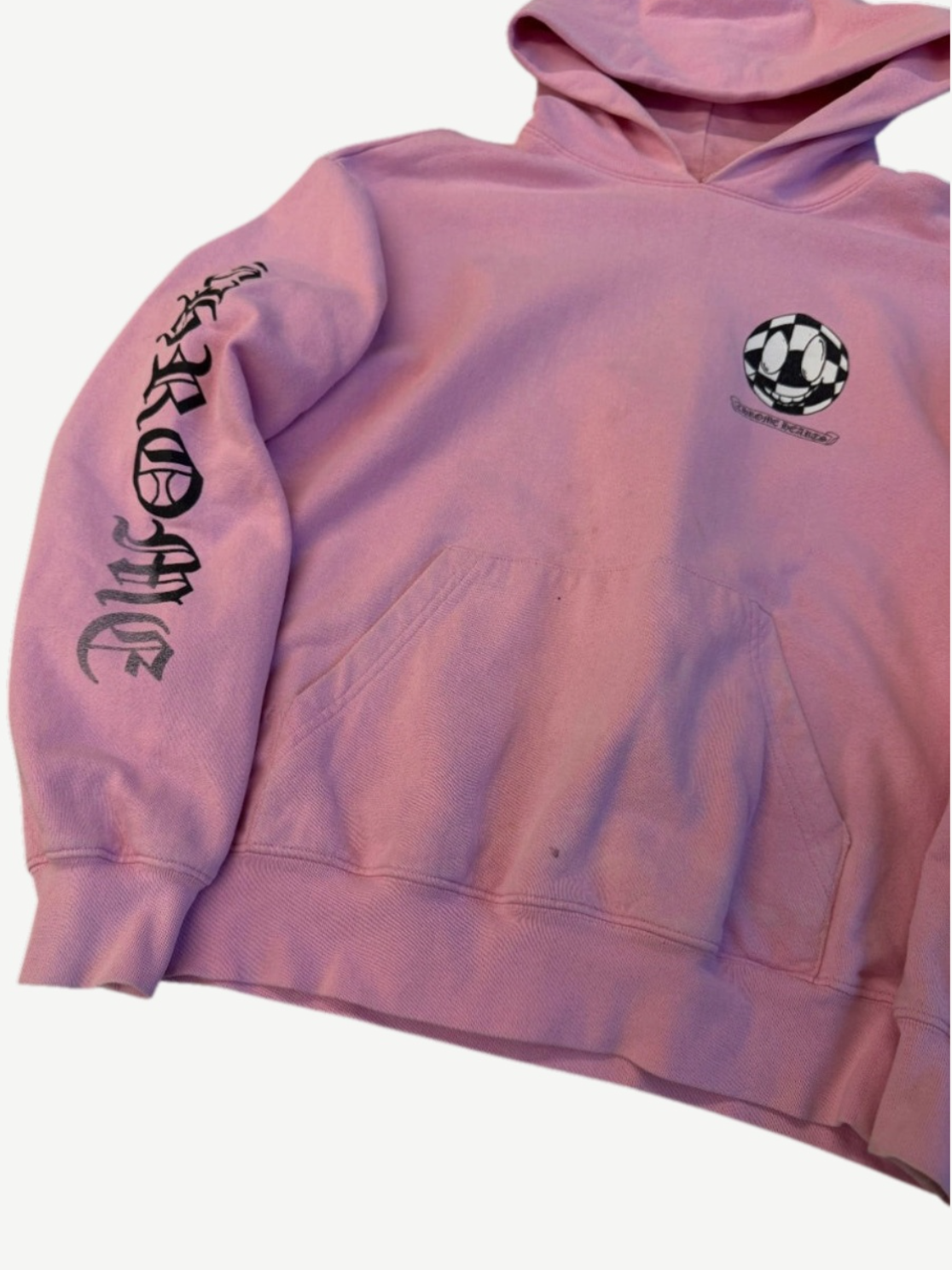 Chrome Hearts Matty Boy pink hoodie cropped detail showing checker smiley face patch and Hearts sleeve script.