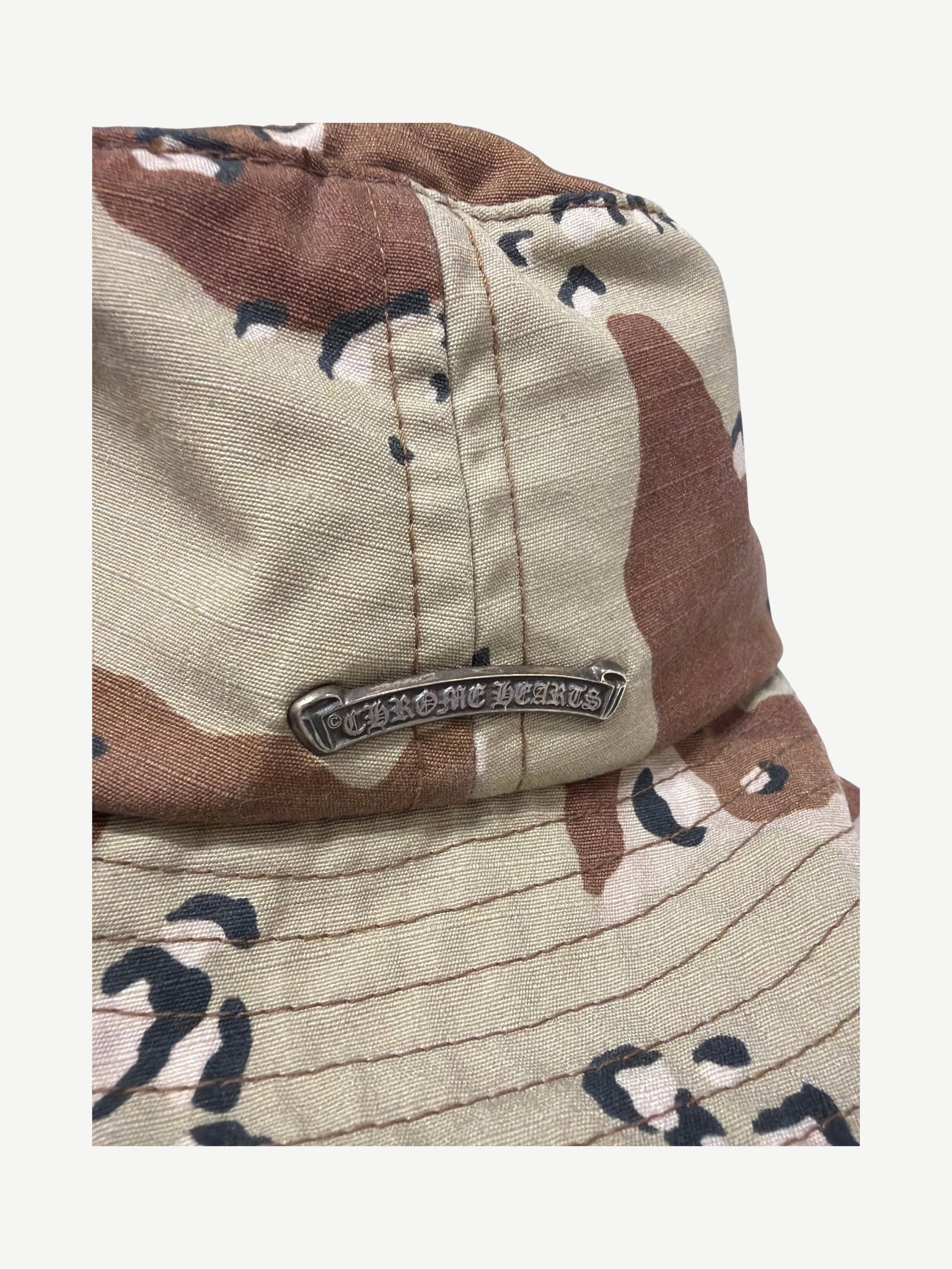 Chrome Hearts desert camo bucket hat close up of side panel with silver Chrome Hearts metal nameplate
