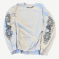 Chrome Hearts white crewneck sweatshirt with black floral cross prints down both sleeves, front view.