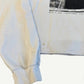 ERD off-white longsleeve close-up of left cuff and lower hem showing ribbed cuff and typewriter text fragments.